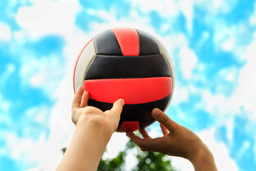 volleyball ball in the hands of a teenager on a background of clear sky