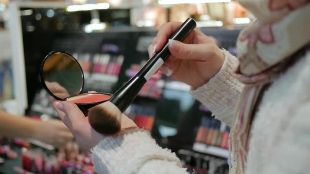 Cosmetologist in beauty salon does makeup to sexy girl, Young female makes purchase Artistic maquillage in mall, In hands powder, brush for make up and mirror, Sexy blonde with bright make-up,