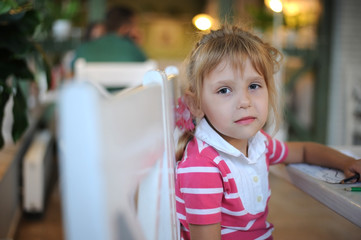 Beautiful girl in a cafe waiting for the ordered dessert. Cafe furnished with white furniture