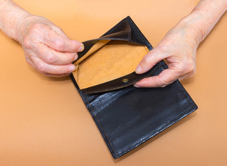 Senior woman sitting on window sill with empty purse, closeup.