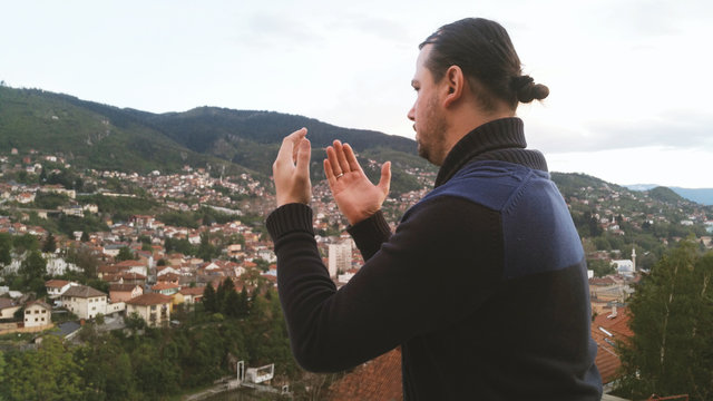 Young adult man praying outdoor with hands up in the air