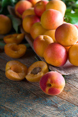 Juicy fresh apricots with leaves on old wooden table .
