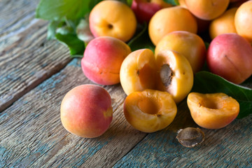 Juicy fresh apricots with leaves on old wooden table .