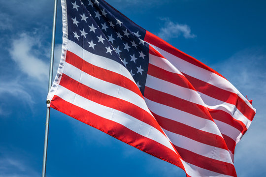 Horizontal photo of a red, white and blue American flag on a silver pole waving in the breeze