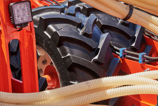 Fragment of a seeder with grain feeding hoses and wheels