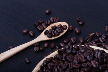 Coffee beans with wood dish and wood spoon on background black