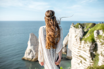 Young woman dressed in hippie style enjoying nature standing back on the rocky coastline with great...