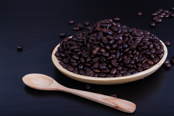 Coffee beans with wood dish and wood spoon on background black