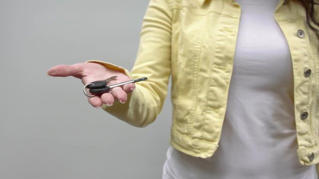 An unrecognizable woman holds out keys to the camera.