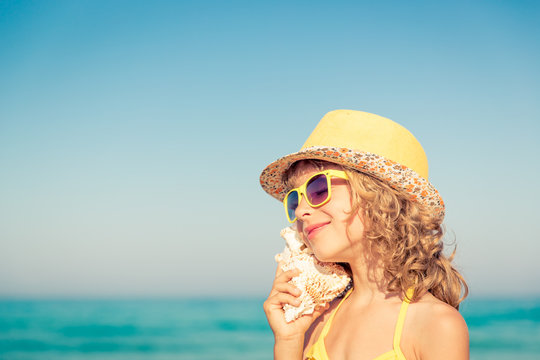 Happy child listen seashell on the beach