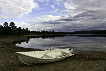 Unidentified white rowboat at isolated Lake Sevettijarvi, Lapland, Finland, under cloudy sky