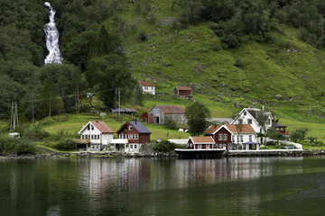 Fototapeta premium Waterfall an small village on shore of Sognefjord fjord, Norway