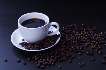Hot coffee in the white cup and roasted on dark background
