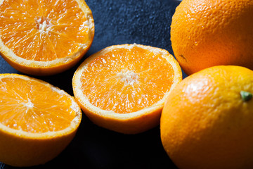 fresh organic oranges halves and juice on black background