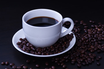 Hot coffee in the white cup and roasted on dark background
