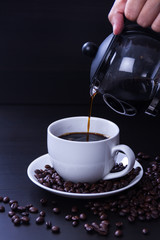 Hot coffee in the white cup and roasted on dark background
