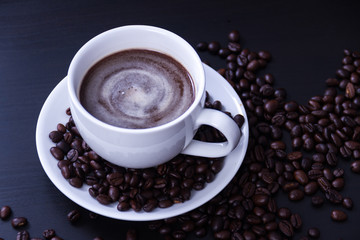 Hot coffee in the white cup and roasted on dark background
