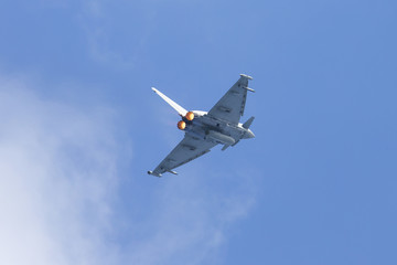 Modern tactical jet fighter flying really close by. Afterburner on, glowing orange.