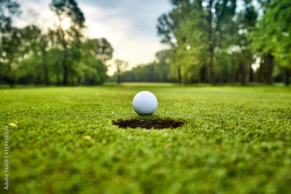 Wall mural Golf ball on the green. golf ball on lip of cup