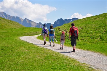 Wanderer wandern auf Wanderweg in den Schweizer Berge,. Im Hintergrund der Berg Hoh Brisen (Gipfel der Urner Alpen) - obrazy, fototapety, plakaty