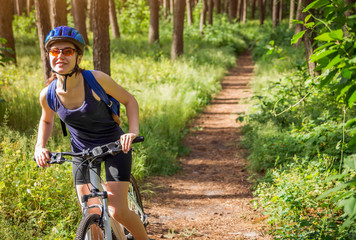 Obraz premium Young woman riding a bicycle in the forest