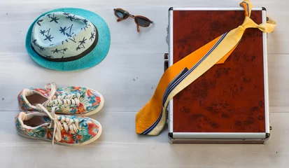Foto op Canvas Suitcase, summer hat and sneakers on a white wooden table © serikbaib