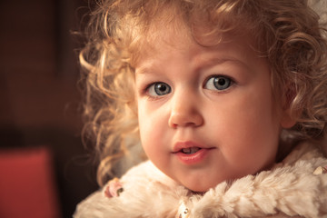 Beautiful curly baby girl like princess portrait with fur jacket