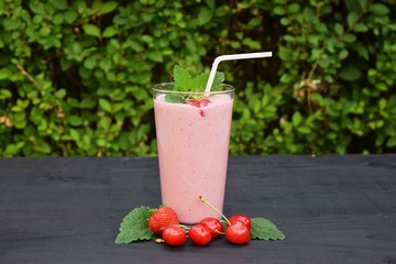 glass of strawberries, cherries smoothie with straw on wooden table. Protein cocktail. Healthy drink. Fresh homemade smoothie. Healthy breakfast of smoothie,