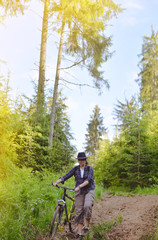 The girl is riding a bicsycle in the woods