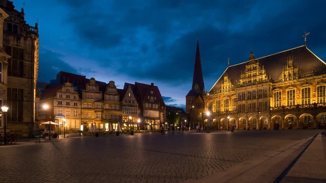 Bremen rathaus (city hall square) at evening time lapse. A lot of bicycles and people walks around the square. Some guy sit on the stairs to surf on the internet.  