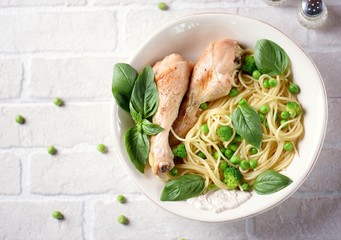 Baked chicken legs with pasta, green peas, broccoli and basil. Top view
