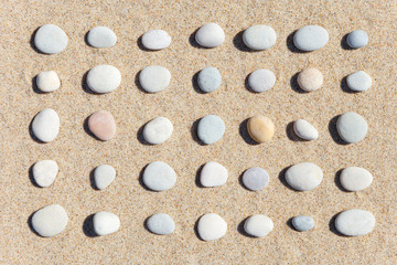 Pattern of white stones on sand background. Flat lay, top view