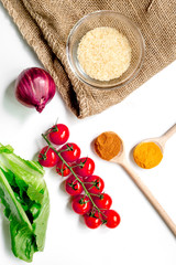 rice, spices and vegetables for paella on white desk background top view