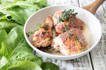 Fototapeta premium Fried golden chicken thighs with spices and herbs. Baked chicken legs