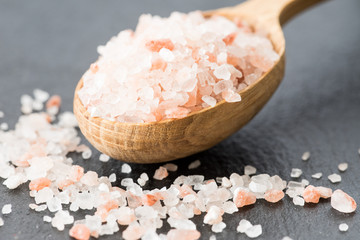 Fototapeta na wymiar Himalayan pink crystal salt. spoon of pink himalayan salt on slate plate