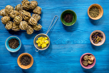 herbs in colorful bowls to make tea on blue table background top view
