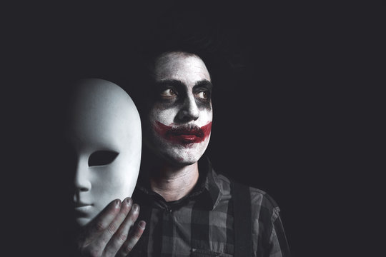 clown holds white mask