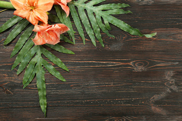 Composition with green tropical leaves and flowers on wooden background