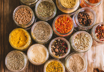 Various colorful kinds of spices on rustic wooden table, top view