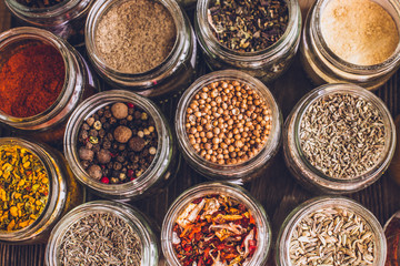 Various colorful kinds of spices on rustic wooden table, top view
