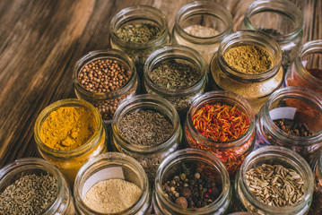 Various colorful kinds of spices on rustic wooden table, top view