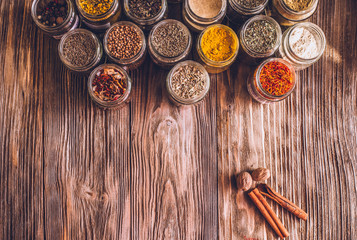 Various colorful kinds of spices on rustic wooden table, top view with copy space