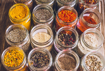 Various colorful kinds of spices on rustic wooden table, top view