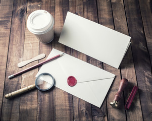 Photo of blank stationery set on wood table background. Blank envelope, postcard, magnifier, seal,...