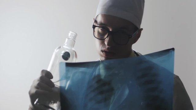 Drunk doctor makes a diagnosis. A medical worker drinks vodka.