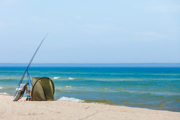 Fototapeta na wymiar Fishing rod and tent on sea shore