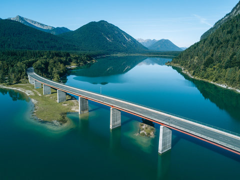 Aerial view of bridge over Sylvenstein Dam with mountain in background