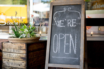 Home made farmhouse style We're open sign outside of a small business	