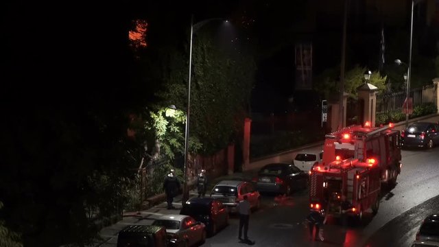 Greek Fire Service tracks during fire at Thessaloniki, Greece. Hellenic Fire Brigade vehicles with Greek firefighters in uniform during a city fire at night.