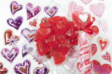 Bowl of red heart candies on a white surface covered with heart stickers.